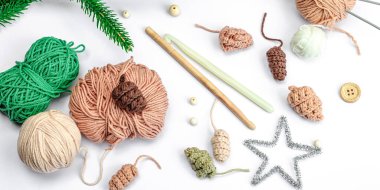 Yaratıcı el yapımı kış yatağı. Sıcak örülü çam kozalakları, geleneksel dekor, aletler, el işi ruh hali konsepti. Beyaz arkaplan, yemyeşil Noel ağacı dalı, afiş biçimi