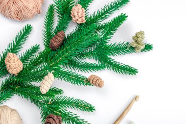 Yaratıcı el yapımı kış yatağı. Sıcak örülü çam kozalakları, geleneksel dekor, aletler, el işi ruh hali konsepti. Beyaz arka plan, yemyeşil Noel ağacı dalı, üst manzara