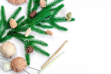 Yaratıcı el yapımı kış yatağı. Sıcak örülü çam kozalakları, geleneksel dekor, aletler, el işi ruh hali konsepti. Beyaz arka plan, yemyeşil Noel ağacı dalı, üst manzara