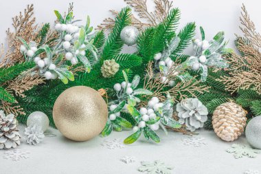 Geleneksel yeni yıl kompozisyonu. Şenlikli dekor, karlı Noel ağacı dalları, takılar, kozalaklar. Hafif taş arkaplan, kapat