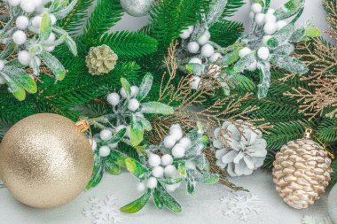 Geleneksel yeni yıl kompozisyonu. Şenlikli dekor, karlı Noel ağacı dalları, takılar, kozalaklar. Hafif taş arkaplan, kapat