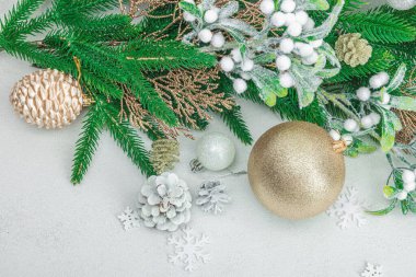 Geleneksel yeni yıl kompozisyonu. Şenlikli dekor, karlı Noel ağacı dalları, takılar, kozalaklar. Hafif taş arkaplan, üst görünüm