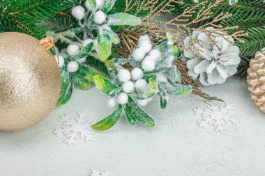 Geleneksel yeni yıl kompozisyonu. Şenlikli dekor, karlı Noel ağacı dalları, takılar, kozalaklar. Hafif taş arkaplan, boşluğu kopyala