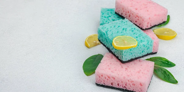 Various sponges for washing dishes. Organic cleaning concept, lemon freshness. Stone concrete background, flat lay, banner format