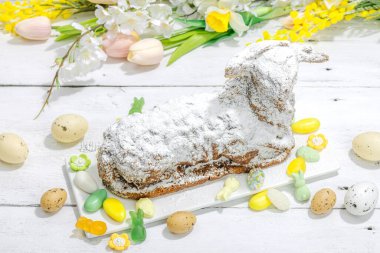 Geleneksel bahar dekorlu Paskalya kuzu pastası. Şekerli, fırında tatlı. Şenlik arka planı, klasik tatil sembolleri. Beyaz tahta arkaplan
