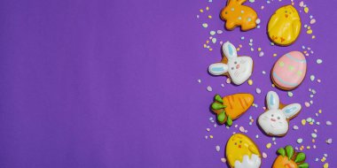 Geleneksel Paskalya kurabiyeleri, yenilebilir şenlik dekorları. Ev yapımı pişirme konsepti, tatlı tatlılar. Tebrik kartı, mor arkaplan, düz yatış, pankart biçimi