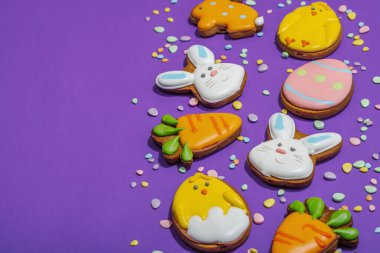 Geleneksel Paskalya kurabiyeleri, yenilebilir şenlik dekorları. Ev yapımı pişirme konsepti, tatlı tatlılar. Tebrik kartı, mor arkaplan, düz yatış, kopyalama alanı