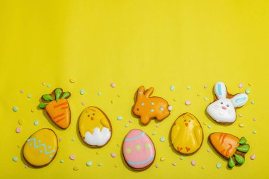 Geleneksel Paskalya kurabiyeleri, yenilebilir şenlik dekorları. Ev yapımı pişirme konsepti, tatlı tatlılar. Tebrik kartı, sarı arkaplan, düz yatak, üst manzara