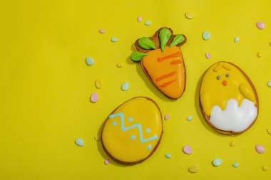 Geleneksel Paskalya kurabiyeleri, yenilebilir şenlik dekorları. Ev yapımı pişirme konsepti, tatlı tatlılar. Tebrik kartı, sarı arkaplan, düz yatak, üst manzara