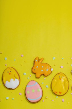 Geleneksel Paskalya kurabiyeleri, yenilebilir şenlik dekorları. Ev yapımı pişirme konsepti, tatlı tatlılar. Tebrik kartı, sarı arkaplan, düz yatak, üst manzara