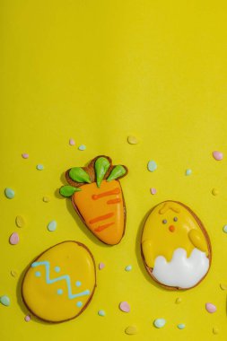 Geleneksel Paskalya kurabiyeleri, yenilebilir şenlik dekorları. Ev yapımı pişirme konsepti, tatlı tatlılar. Tebrik kartı, sarı arkaplan, düz yatak, üst manzara