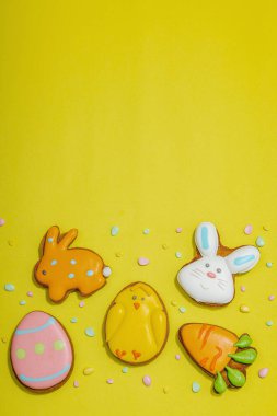 Geleneksel Paskalya kurabiyeleri, yenilebilir şenlik dekorları. Ev yapımı pişirme konsepti, tatlı tatlılar. Tebrik kartı, sarı arkaplan, düz yatak, üst manzara