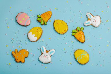 Geleneksel Paskalya kurabiyeleri, yenilebilir şenlik dekorları. Ev yapımı pişirme konsepti, tatlı tatlılar. Tebrik kartı, mavi arkaplan, düz yatak, üst görünüm