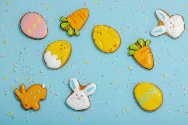 Geleneksel Paskalya kurabiyeleri, yenilebilir şenlik dekorları. Ev yapımı pişirme konsepti, tatlı tatlılar. Tebrik kartı, mavi arkaplan, düz yatak, üst görünüm