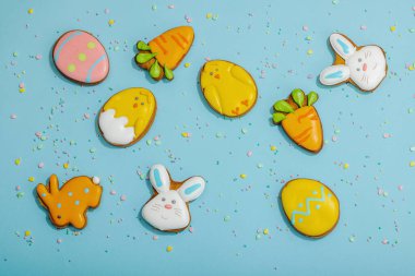 Geleneksel Paskalya kurabiyeleri, yenilebilir şenlik dekorları. Ev yapımı pişirme konsepti, tatlı tatlılar. Tebrik kartı, mavi arkaplan, düz yatak, üst görünüm