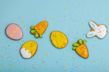 Geleneksel Paskalya kurabiyeleri, yenilebilir şenlik dekorları. Ev yapımı pişirme konsepti, tatlı tatlılar. Tebrik kartı, mavi arkaplan, düz yatak, üst görünüm