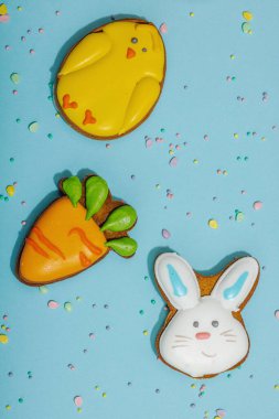 Geleneksel Paskalya kurabiyeleri, yenilebilir şenlik dekorları. Ev yapımı pişirme konsepti, tatlı tatlılar. Tebrik kartı, mavi arkaplan, düz yatak, üst görünüm