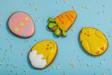 Geleneksel Paskalya kurabiyeleri, yenilebilir şenlik dekorları. Ev yapımı pişirme konsepti, tatlı tatlılar. Tebrik kartı, mavi arkaplan, düz yatak, üst görünüm