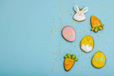 Geleneksel Paskalya kurabiyeleri, yenilebilir şenlik dekorları. Ev yapımı pişirme konsepti, tatlı tatlılar. Tebrik kartı, mavi arkaplan, düz yatak, üst görünüm