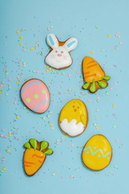 Geleneksel Paskalya kurabiyeleri, yenilebilir şenlik dekorları. Ev yapımı pişirme konsepti, tatlı tatlılar. Tebrik kartı, mavi arkaplan, düz yatak, üst görünüm