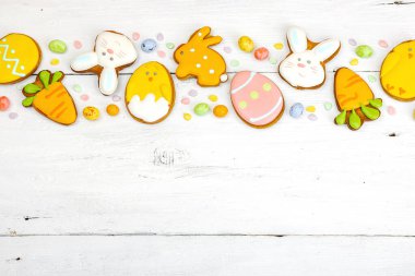 Geleneksel Paskalya kurabiyeleri, yenilebilir şenlik dekorları. Ev yapımı pişirme konsepti, tatlı tatlılar. Tebrik kartı, beyaz ahşap zemin, düz yatış, üst manzara