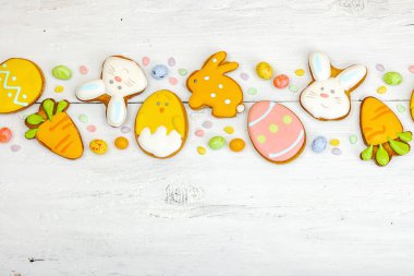 Geleneksel Paskalya kurabiyeleri, yenilebilir şenlik dekorları. Ev yapımı pişirme konsepti, tatlı tatlılar. Tebrik kartı, beyaz ahşap zemin, düz yatış, üst manzara