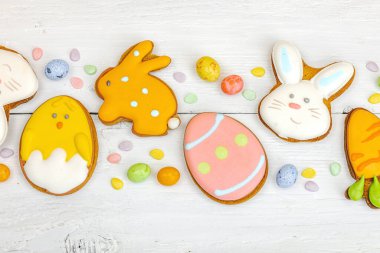 Geleneksel Paskalya kurabiyeleri, yenilebilir şenlik dekorları. Ev yapımı pişirme konsepti, tatlı tatlılar. Tebrik kartı, beyaz ahşap zemin, düz yatış, üst manzara