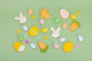 Geleneksel Paskalya kurabiyeleri, yenilebilir şenlik dekorları. Ev yapımı pişirme konsepti, tatlı tatlılar. Tebrik kartı, pastel yeşil arkaplan, düz yatak, üst görünüm