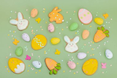 Geleneksel Paskalya kurabiyeleri, yenilebilir şenlik dekorları. Ev yapımı pişirme konsepti, tatlı tatlılar. Tebrik kartı, pastel yeşil arkaplan, düz yatak, üst görünüm