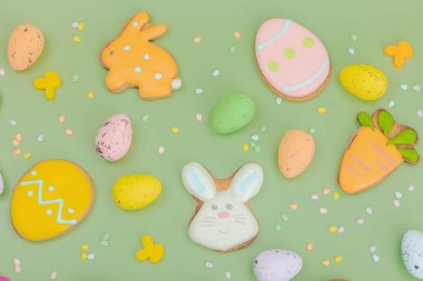 Geleneksel Paskalya kurabiyeleri, yenilebilir şenlik dekorları. Ev yapımı pişirme konsepti, tatlı tatlılar. Tebrik kartı, pastel yeşil arkaplan, düz yatak, üst görünüm