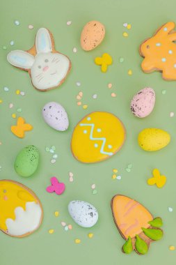 Geleneksel Paskalya kurabiyeleri, yenilebilir şenlik dekorları. Ev yapımı pişirme konsepti, tatlı tatlılar. Tebrik kartı, pastel yeşil arkaplan, düz yatak, üst görünüm