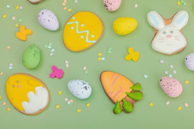 Geleneksel Paskalya kurabiyeleri, yenilebilir şenlik dekorları. Ev yapımı pişirme konsepti, tatlı tatlılar. Tebrik kartı, pastel yeşil arkaplan, düz yatak, üst görünüm