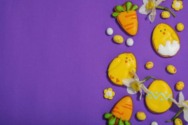 Geleneksel Paskalya kurabiyeleri, yenilebilir şenlik dekorları. Ev yapımı pişirme konsepti, tatlı tatlılar. Tebrik kartı, mor arkaplan, düz yatak, üst görünüm