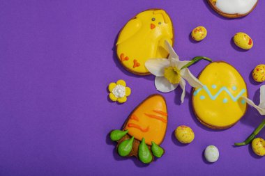 Geleneksel Paskalya kurabiyeleri, yenilebilir şenlik dekorları. Ev yapımı pişirme konsepti, tatlı tatlılar. Tebrik kartı, mor arkaplan, düz yatak, üst görünüm