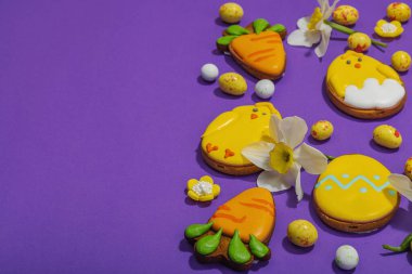 Geleneksel Paskalya kurabiyeleri, yenilebilir şenlik dekorları. Ev yapımı pişirme konsepti, tatlı tatlılar. Tebrik kartı, mor arkaplan, düz yatış, kopyalama alanı
