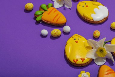 Geleneksel Paskalya kurabiyeleri, yenilebilir şenlik dekorları. Ev yapımı pişirme konsepti, tatlı tatlılar. Tebrik kartı, mor arkaplan, düz yatış, kopyalama alanı