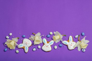 Geleneksel Paskalya kurabiyeleri, yenilebilir şenlik dekorları. Ev yapımı pişirme konsepti, tatlı tatlılar. Tebrik kartı, mor arkaplan, düz yatak, üst görünüm