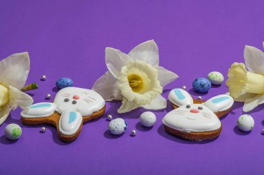 Geleneksel Paskalya kurabiyeleri, yenilebilir şenlik dekorları. Ev yapımı pişirme konsepti, tatlı tatlılar. Tebrik kartı, mor arkaplan, düz yatış, kopyalama alanı