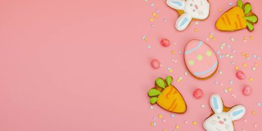 Geleneksel Paskalya kurabiyeleri, yenilebilir şenlik dekorları. Ev yapımı pişirme konsepti, tatlı tatlılar. Tebrik kartı, pembe arkaplan, düz yatış, pankart biçimi