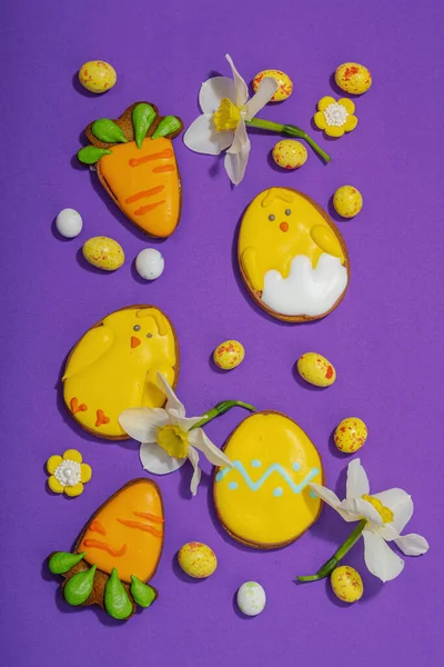 Geleneksel Paskalya kurabiyeleri, yenilebilir şenlik dekorları. Ev yapımı pişirme konsepti, tatlı tatlılar. Tebrik kartı, mor arkaplan, düz yatak, üst görünüm
