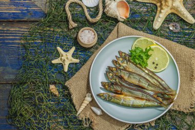 Taze limon ve bitkilerle tütsülenmiş eritilmiş. Deniz dekorlu tuzlu balık. Moda yemeği, deniz ipi. Mavi denizcilik ahşap arka plan, üst görünüm