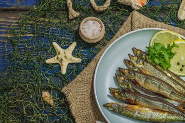 Taze limon ve bitkilerle tütsülenmiş eritilmiş. Deniz dekorlu tuzlu balık. Moda yemeği, deniz ipi. Mavi denizcilik ahşap arka plan, üst görünüm