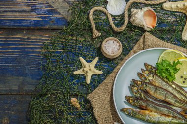 Taze limon ve bitkilerle tütsülenmiş eritilmiş. Deniz dekorlu tuzlu balık. Moda yemeği, deniz ipi. Mavi denizcilik ahşap arka plan, üst görünüm