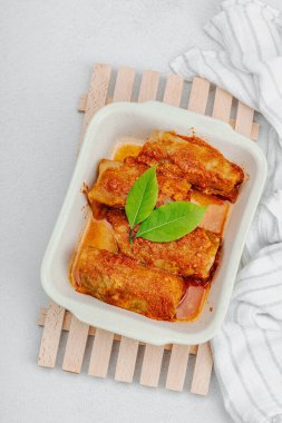 Pirinçle doldurulmuş lahana ruloları ve domates sosunda pişirilmiş et. Geleneksel yemek, hazır yemek, ekşi krema. Hafif taş arkaplan, üst görünüm