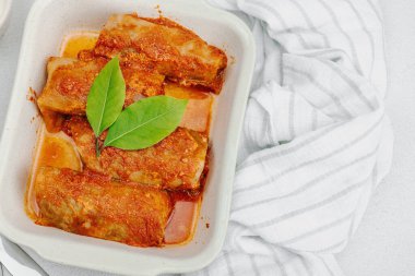 Pirinçle doldurulmuş lahana ruloları ve domates sosunda pişirilmiş et. Geleneksel yemek, hazır yemek, ekşi krema. Hafif taş arkaplan, üst görünüm