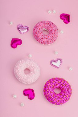 Parlak kalpli el yapımı örülü çörekler. Sevgililer Günü ya da Anneler Günü, tebrik kartı, yaratıcı sanatlar konsepti. Pembe zemin, düz yatış, üst görünüm