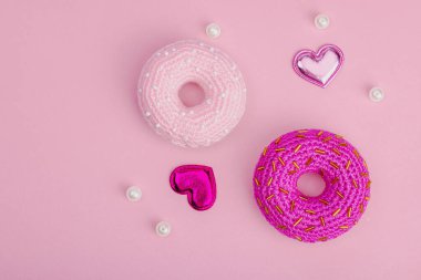 Parlak kalpli el yapımı örülü çörekler. Sevgililer Günü ya da Anneler Günü, tebrik kartı, yaratıcı sanatlar konsepti. Pembe zemin, düz yatış, üst görünüm