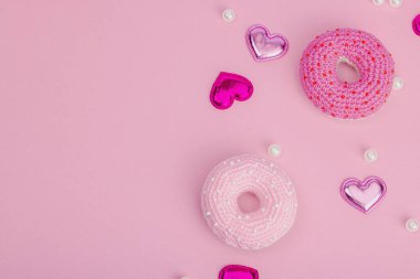 Parlak kalpli el yapımı örülü çörekler. Sevgililer Günü ya da Anneler Günü, tebrik kartı, yaratıcı sanatlar konsepti. Pembe zemin, düz yatış, üst görünüm