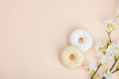 Kiraz dallarıyla örülmüş el yapımı çörekler. Bayramlık Paskalya, tebrik kartı, yaratıcı zanaat konsepti. Moda kayısı arka planı, düz yatış, üst görünüm