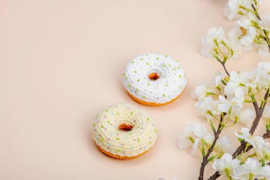 Kiraz dallarıyla örülmüş el yapımı çörekler. Bayramlık Paskalya, tebrik kartı, yaratıcı zanaat konsepti. Moda kayısı arka planı, düz yatış, kopyalama alanı